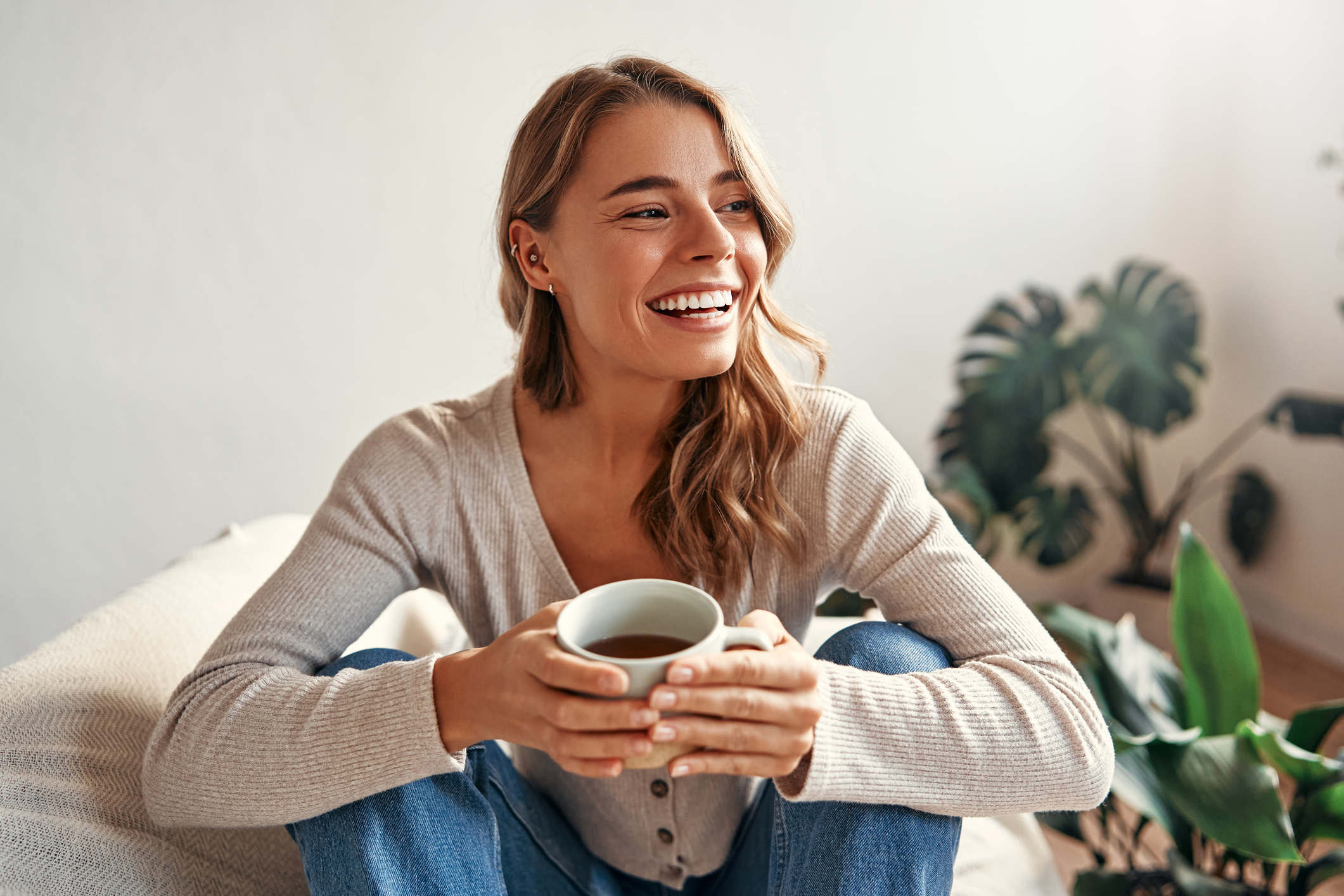 Woman smiling while holding a warm cup of coffee at home