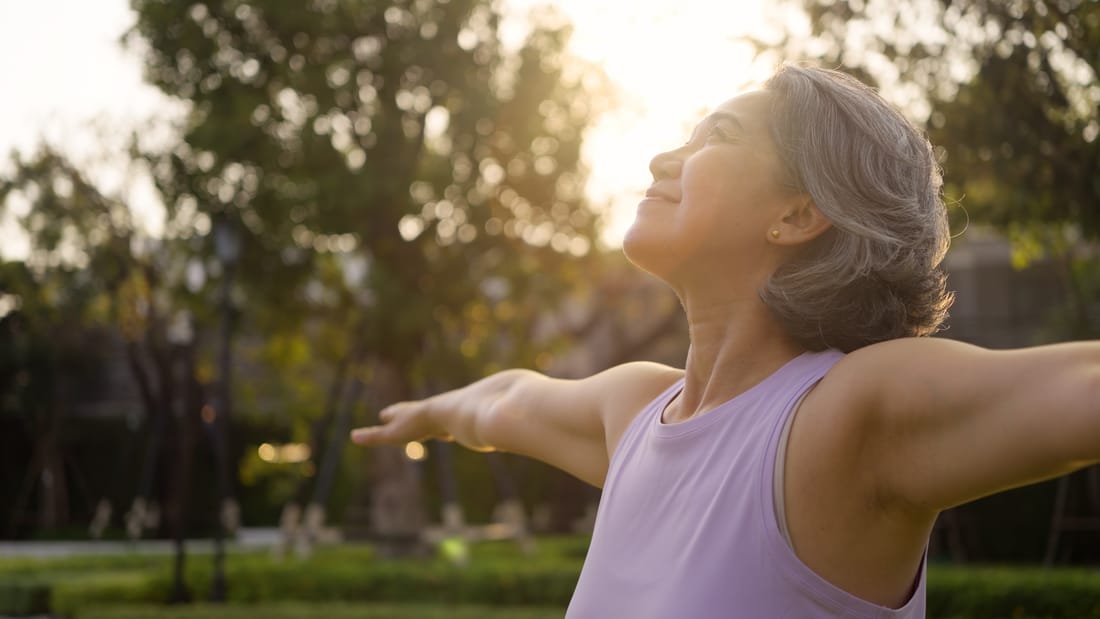 A person outdoors with arms open, feeling well